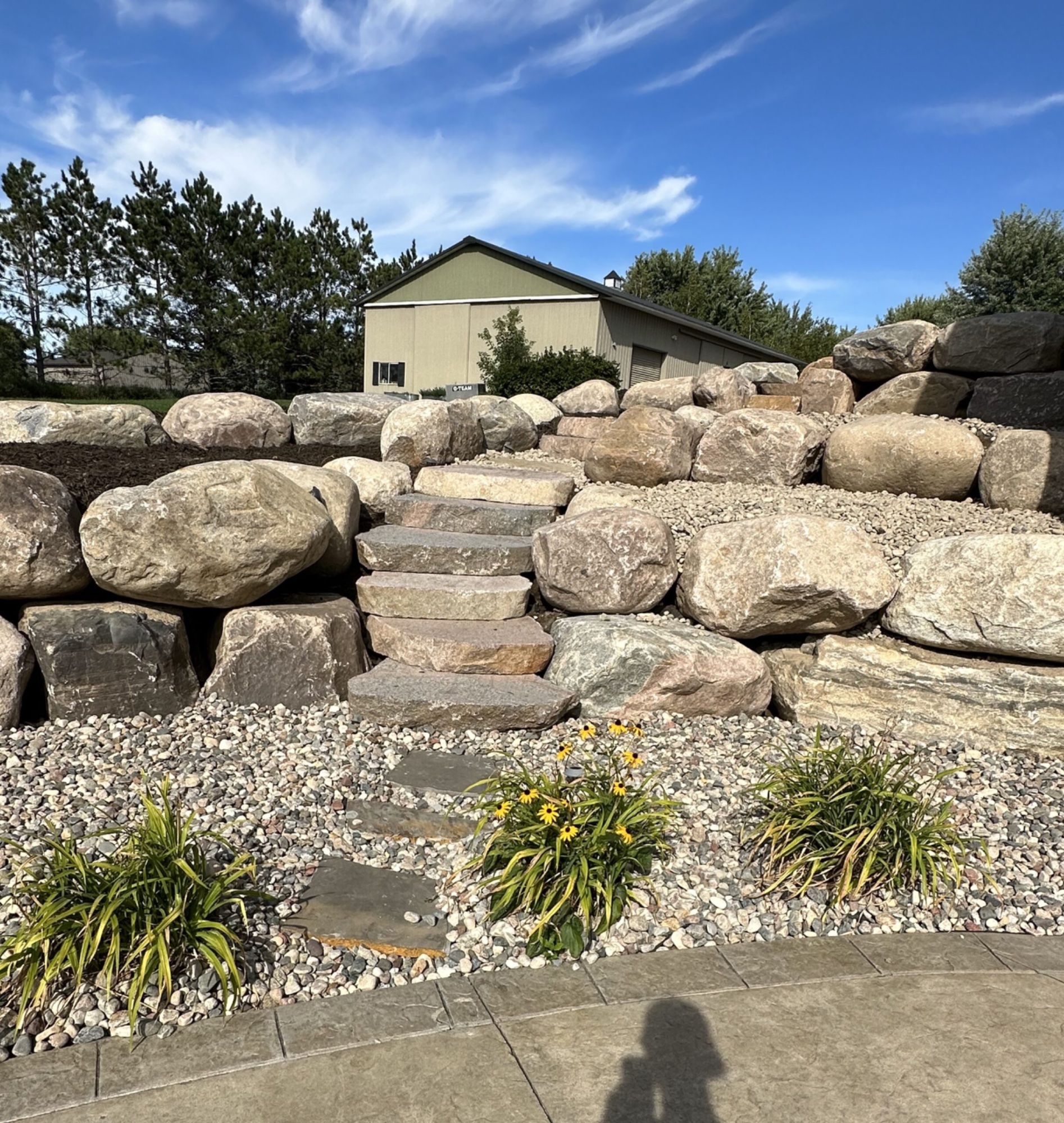 Multi-level boulder retaining wall with natural stone steps by Dakota Earthworks in North Dakota